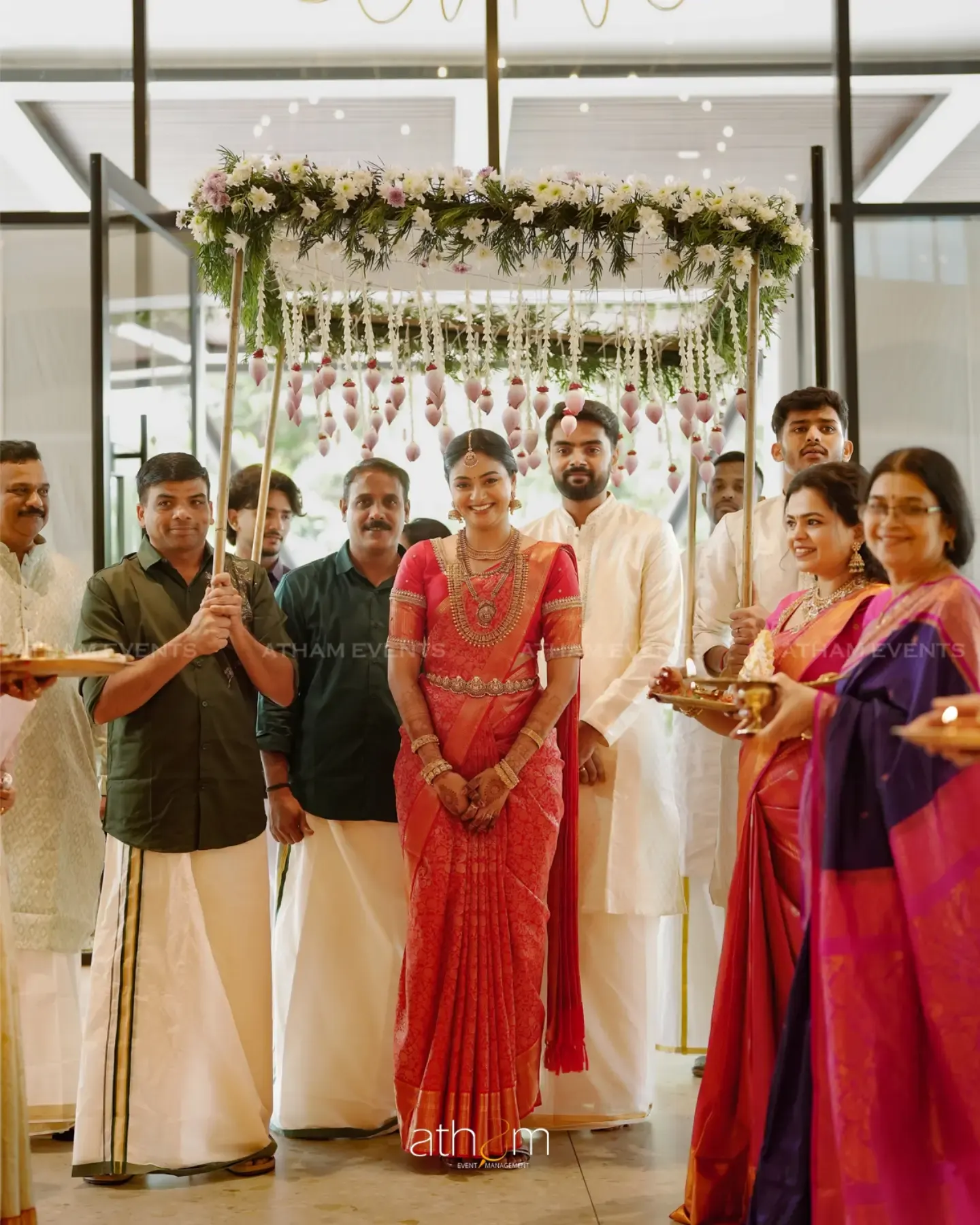 Kerala bride entering beneath a white floral canopy