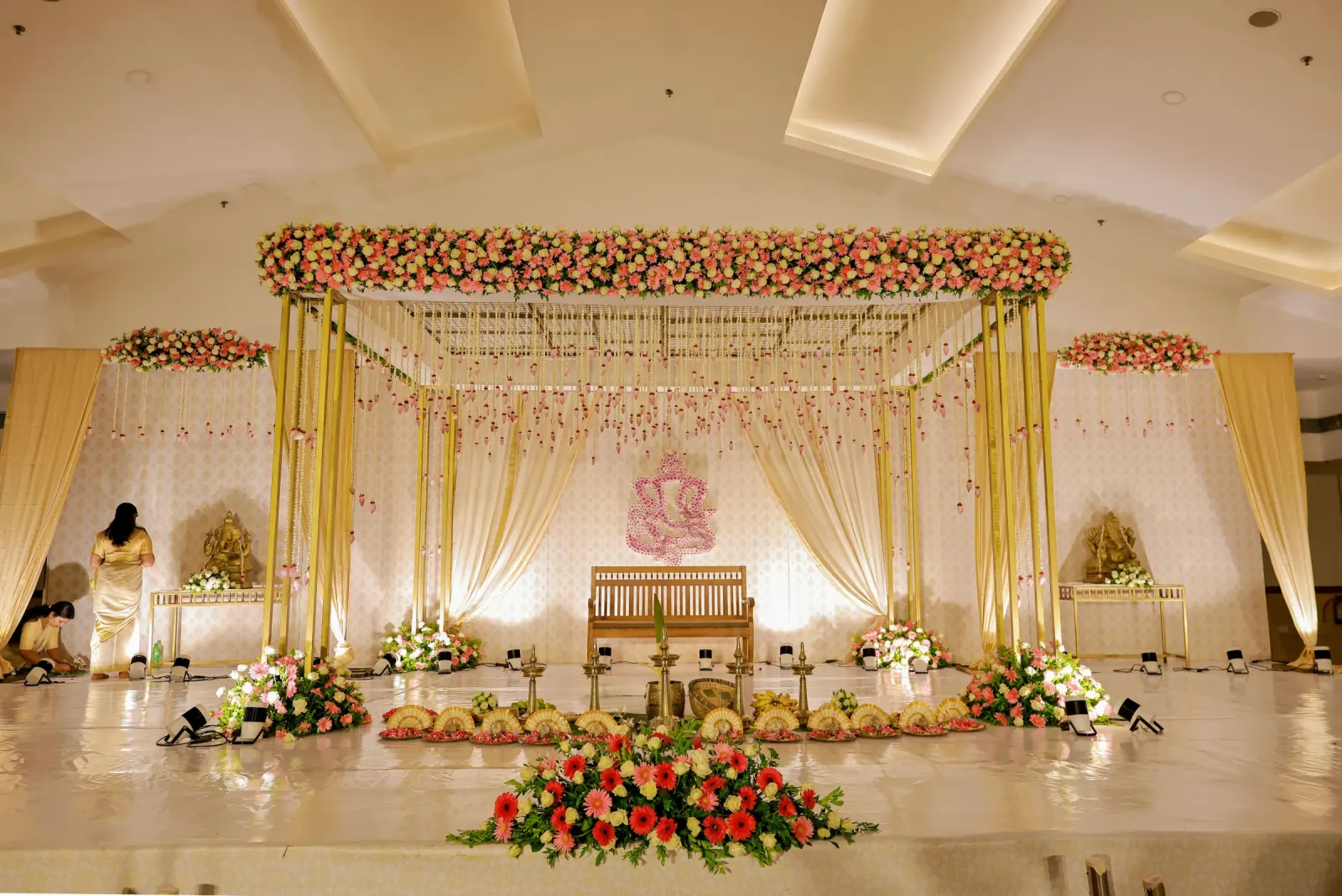 Pastel floral Ganesh wedding stage with ivory drapes and gold frame