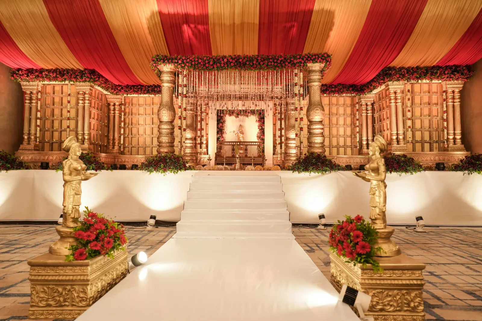 Royal red and gold temple-style wedding stage with floral canopy