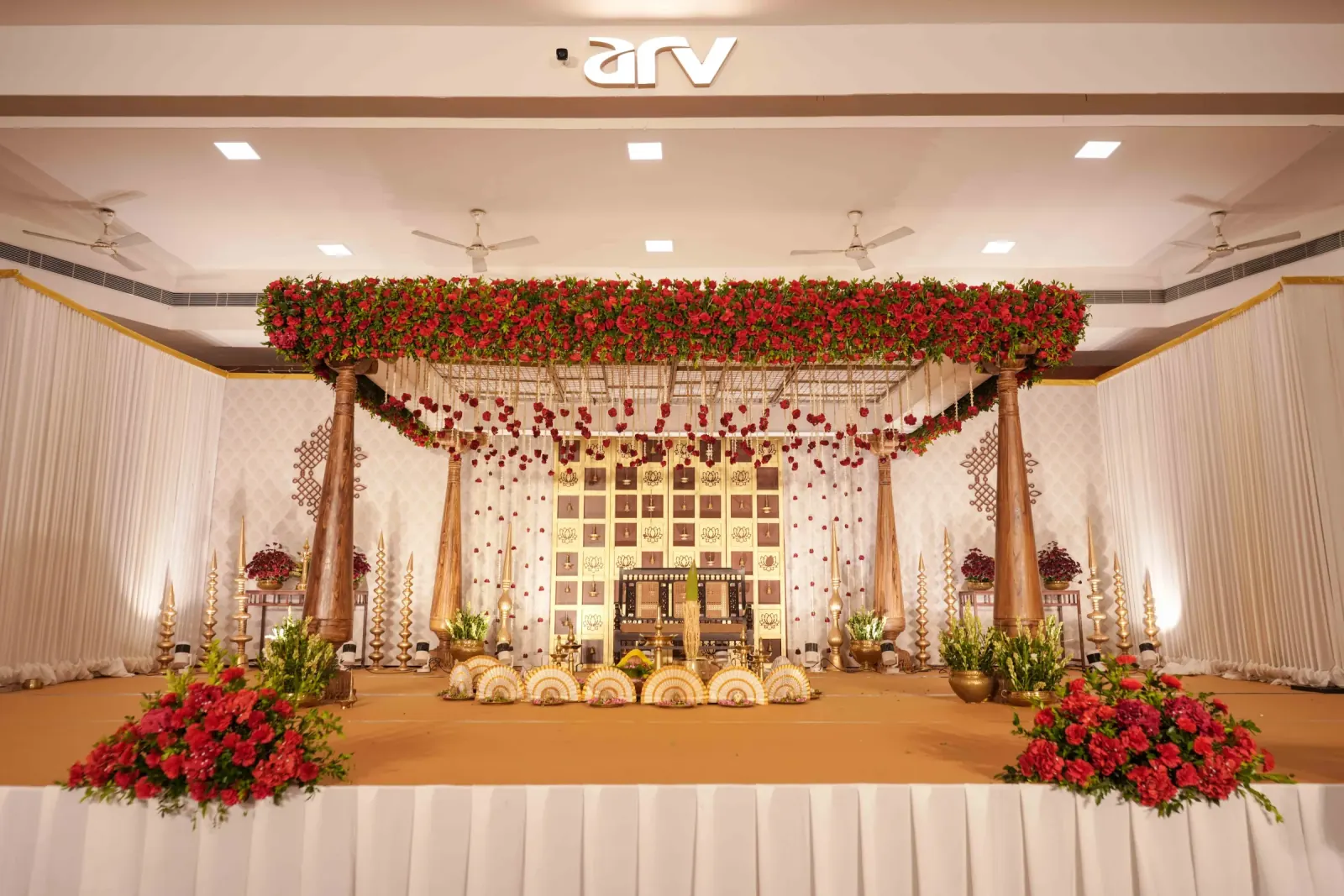 Traditional wooden wedding mandap with red roses and brass lamps