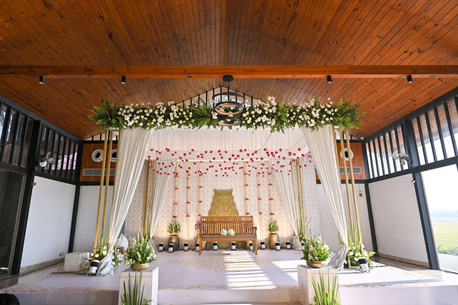White and green traditional wedding stage beneath a wooden ceiling